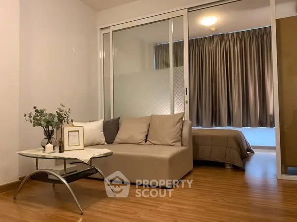 Modern studio apartment with cozy living area and bedroom, featuring elegant decor and wooden flooring.