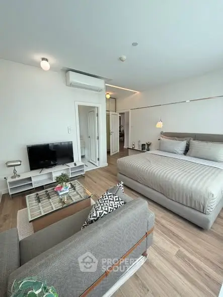 Modern studio apartment with cozy living area and stylish decor, featuring a comfortable bed and sleek furnishings.