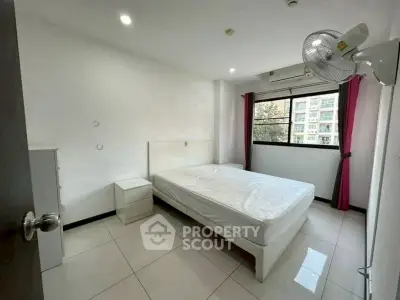 Spacious bedroom with natural light and modern furnishings in urban apartment.