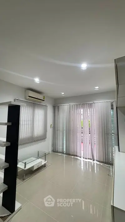 Modern living room with sleek design and natural light, featuring air conditioning and stylish blinds.