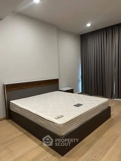 Spacious bedroom with modern design and large window, featuring a comfortable bed and elegant curtains.