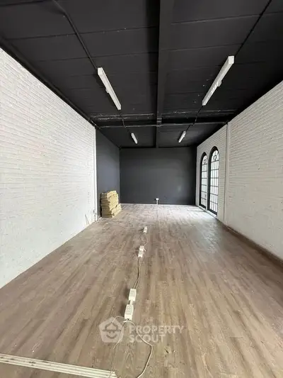 Spacious interior with wooden flooring and large windows, ideal for creative workspace or studio.