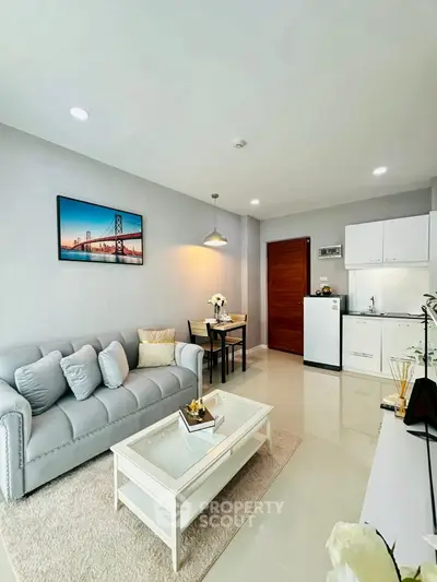 Modern living room with cozy sofa, dining area, and compact kitchen in open layout.