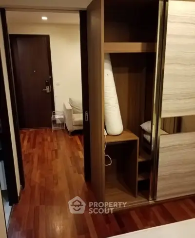 Spacious bedroom with wooden flooring and built-in wardrobe in modern apartment.