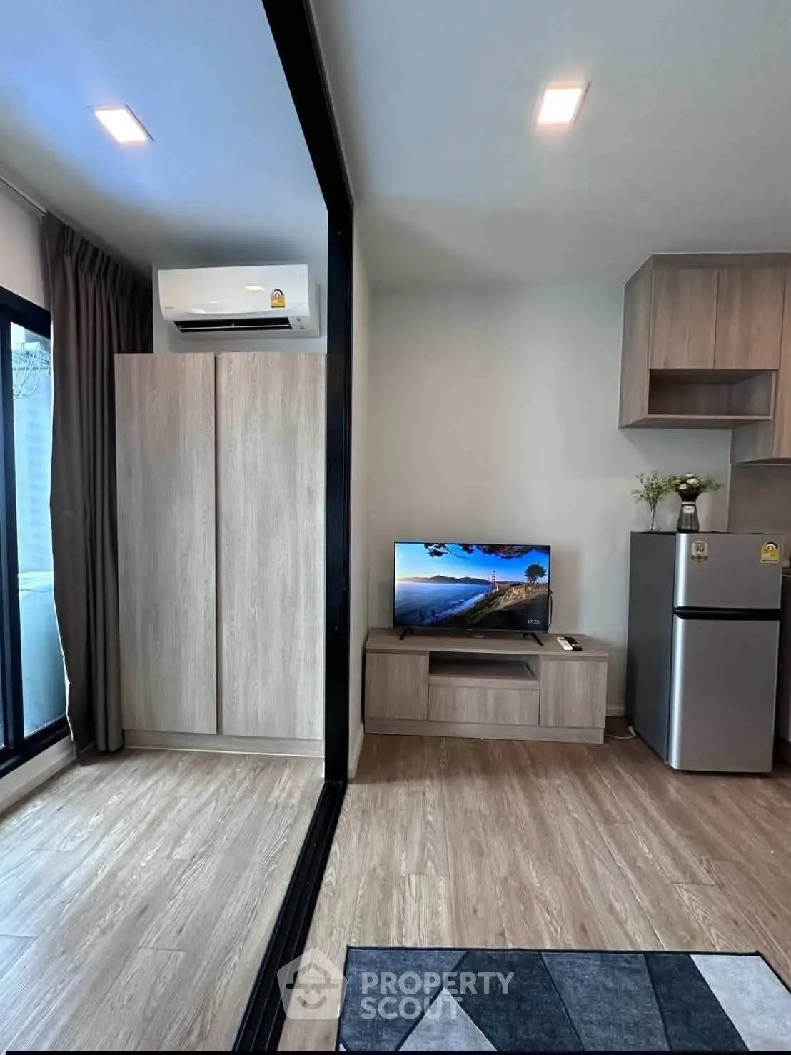 Modern living room with sleek design, featuring air conditioning, TV, and stylish wooden flooring.
