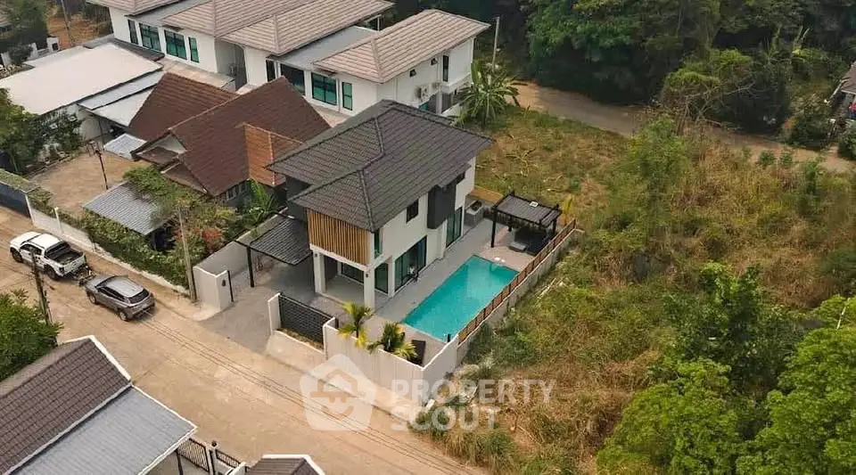 Stunning aerial view of modern house with private pool and lush surroundings, perfect for luxury living.