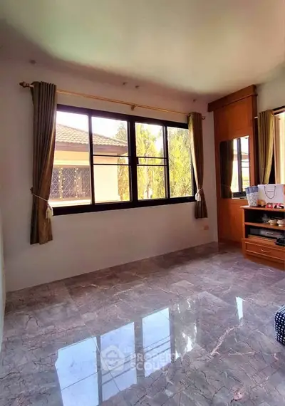 Spacious sunlit room with large window and marble flooring, perfect for a cozy living space.