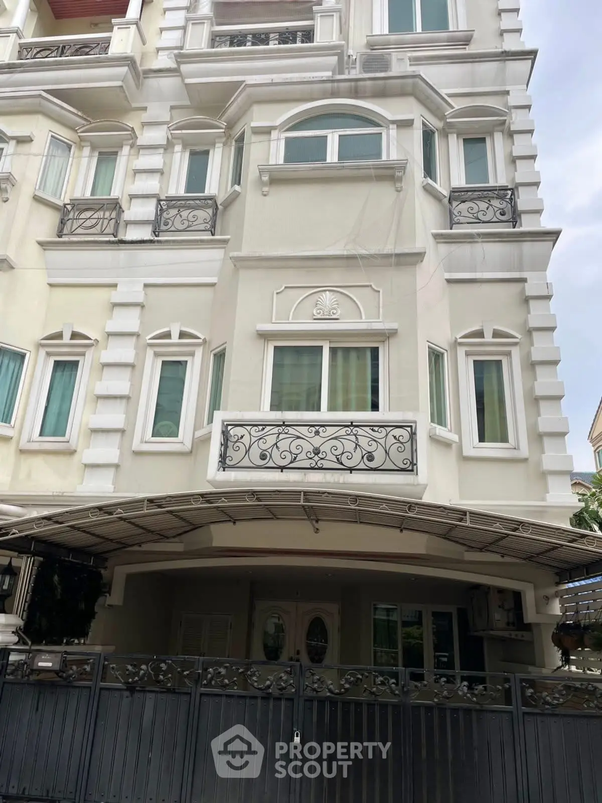 Elegant multi-story residential building with ornate balconies and gated entrance.
