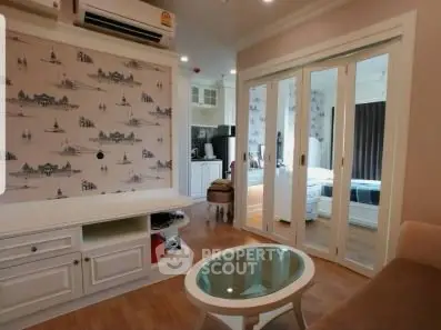 Charming living room with stylish decor and glass doors leading to a cozy bedroom.