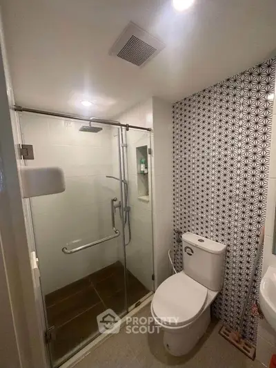 Modern bathroom with glass shower and stylish patterned wall tiles.