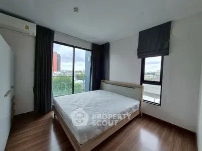 Modern bedroom with large windows and city view, featuring a comfortable bed and stylish decor.