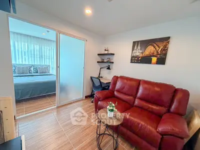Cozy living room with red leather sofa and view into modern bedroom