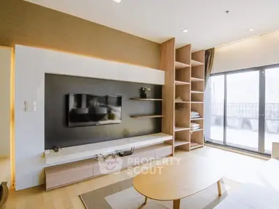 Modern living room with built-in TV unit and large windows offering natural light.