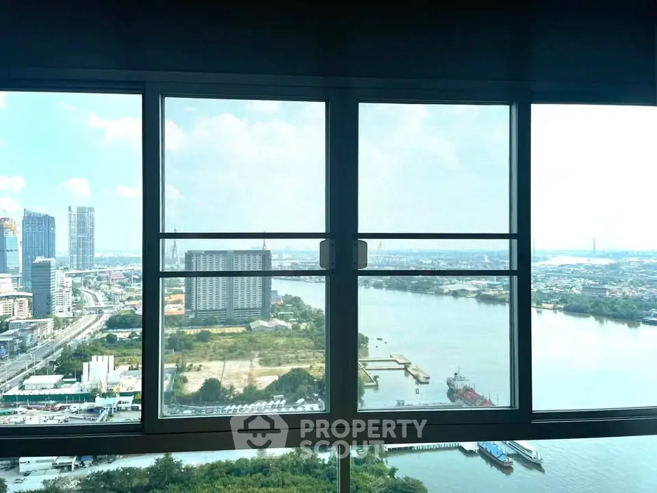 Stunning river view from high-rise apartment window showcasing urban skyline.