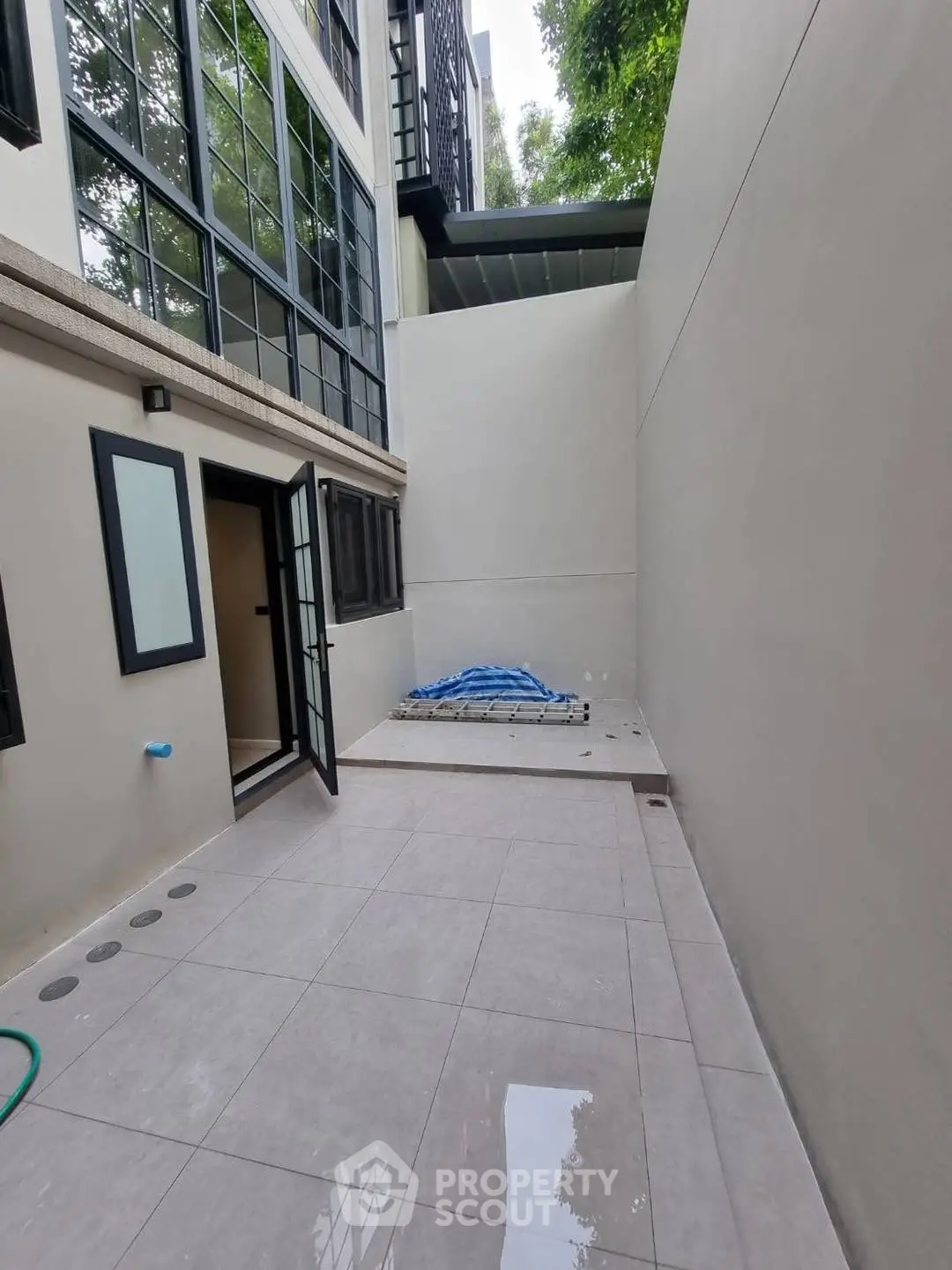 Modern exterior courtyard with sleek tiled flooring and large windows.