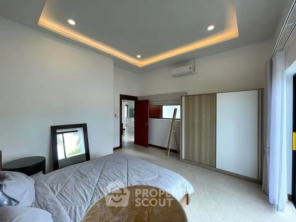 Spacious modern bedroom with elegant lighting and large wardrobe in a stylish home.