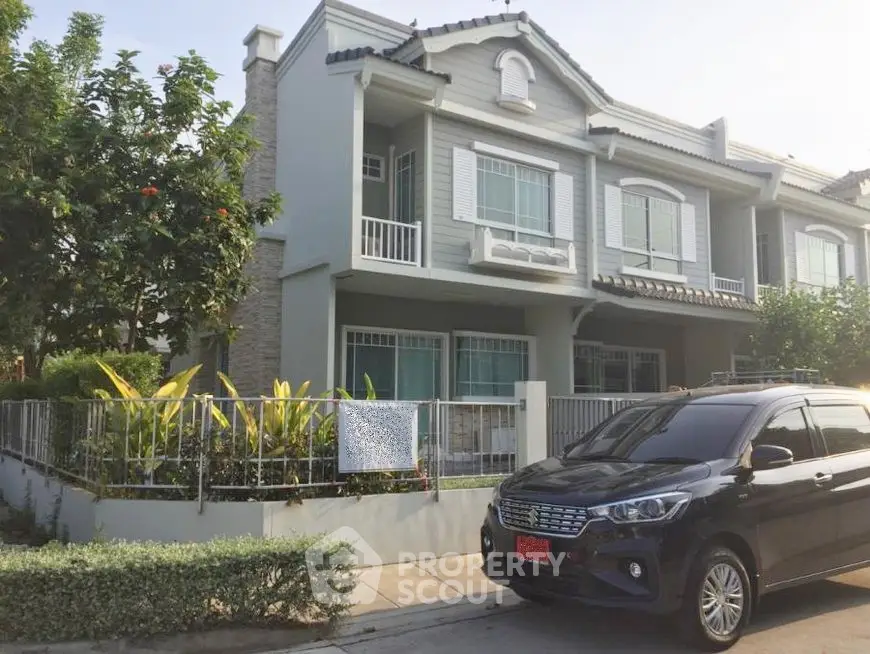 Charming two-story townhouse with modern facade and lush garden in a serene neighborhood.