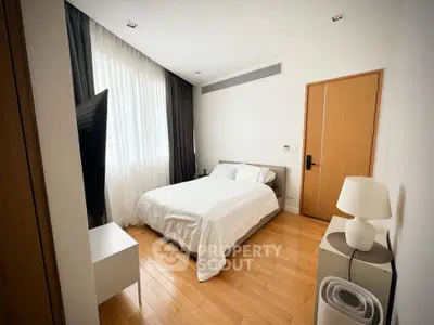 Modern bedroom with wooden flooring and stylish decor in a contemporary apartment.