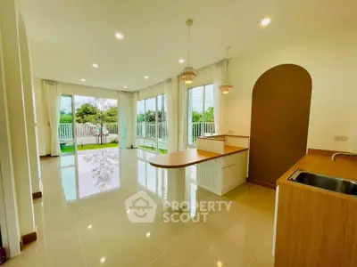Spacious open-layout living room with modern kitchen and large windows overlooking garden.