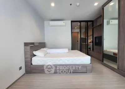 Modern bedroom with sleek design, featuring a large bed, mirrored wardrobe, and minimalist decor.