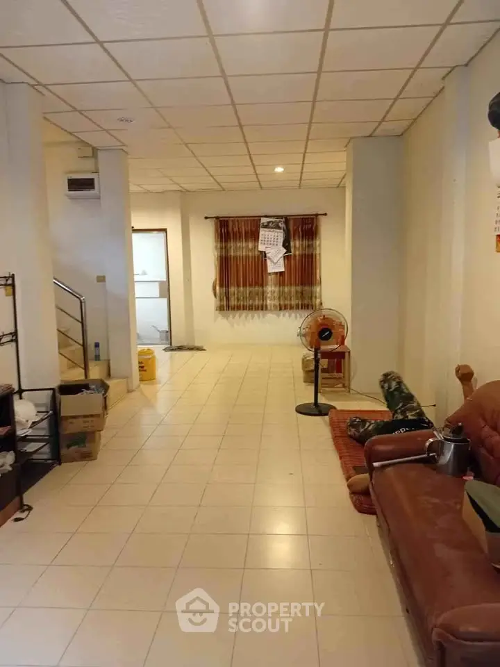 Spacious living room with tiled flooring and cozy seating area, ideal for family gatherings.