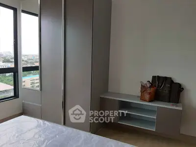 Modern bedroom with large window and built-in wardrobe offering city views.