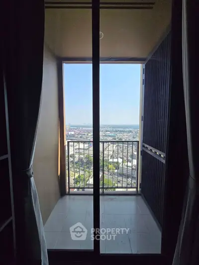 Stunning high-rise balcony view with expansive cityscape and clear blue sky, perfect for urban living.
