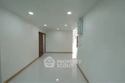 Spacious empty room with white walls and recessed lighting, ideal for customization.