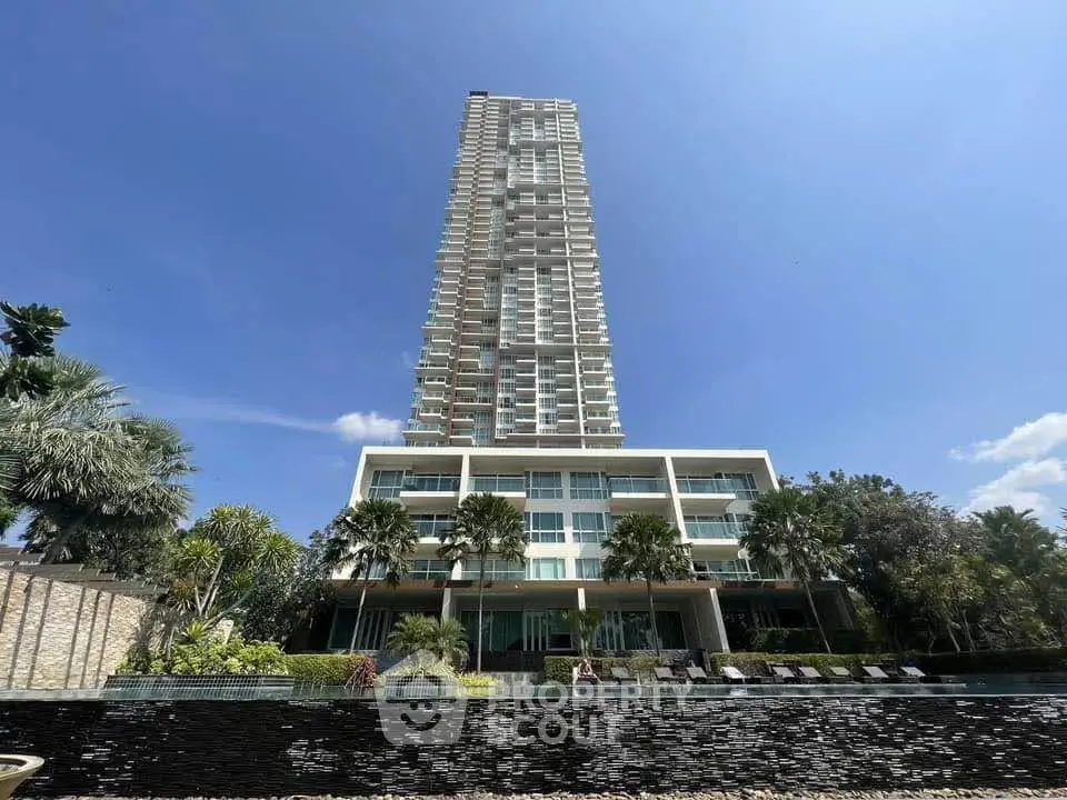 Stunning high-rise building with lush landscaping and pool, offering luxurious urban living.
