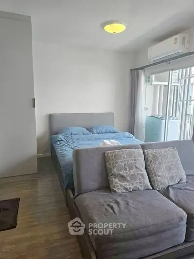 Cozy bedroom with modern decor and natural light, featuring a comfortable bed and stylish sofa.
