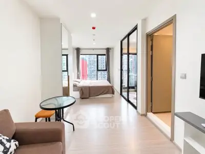 Modern open-plan apartment with spacious living area and bedroom, featuring large windows and city views.