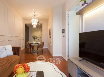 Elegant living room with modern decor and dining area, featuring stylish lighting and cozy seating.