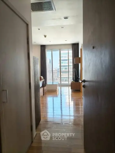 Spacious bedroom with balcony and city view, featuring wooden flooring and modern decor.