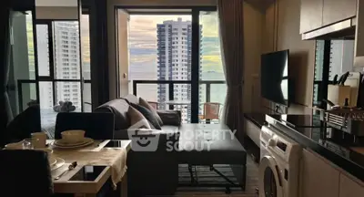 Modern living room with ocean view, stylish furniture, and integrated kitchen appliances in a high-rise apartment.