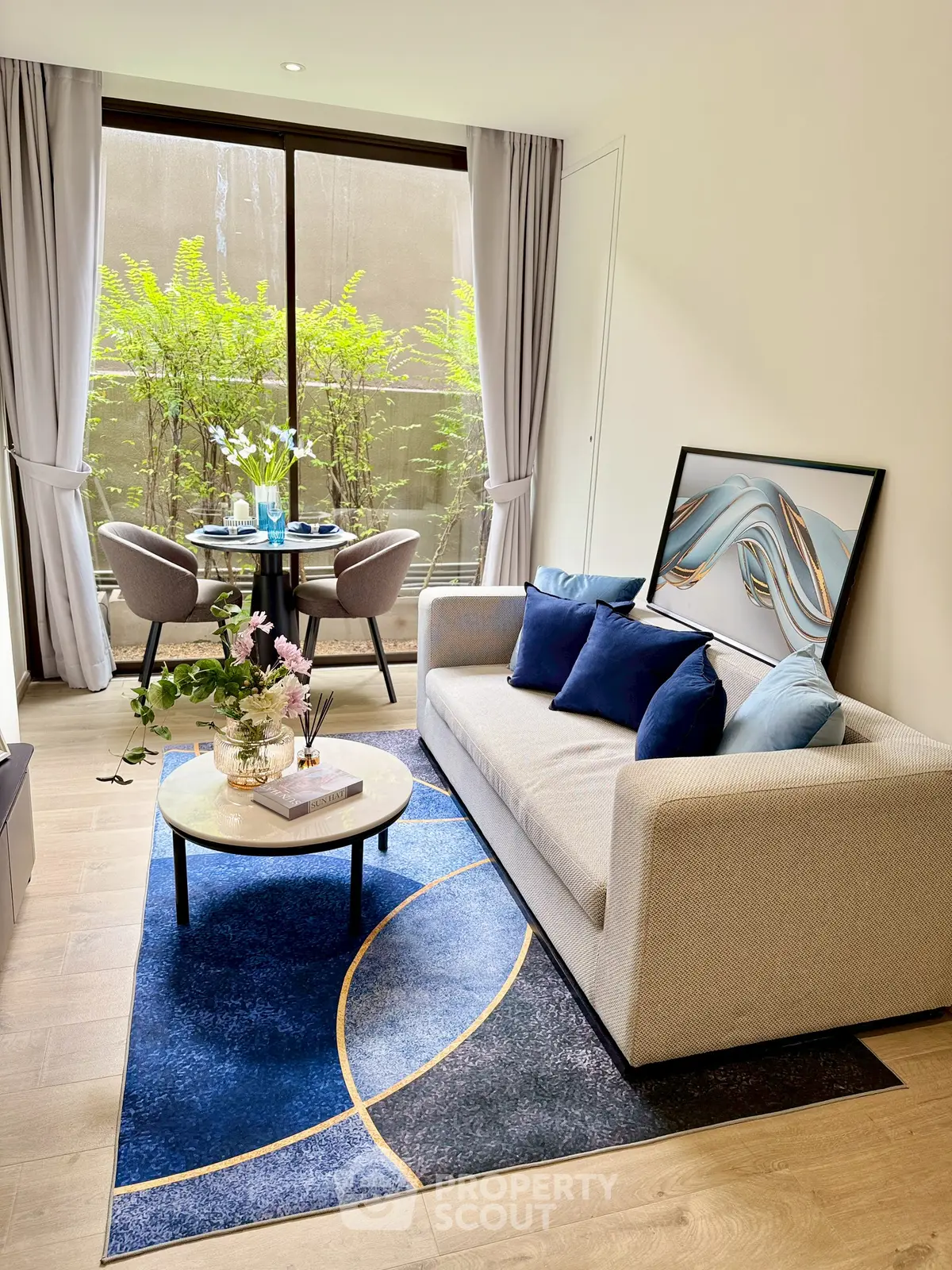 Modern living room with stylish decor, blue accents, and natural light from large window.