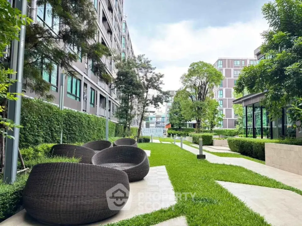 Modern apartment complex with lush green garden and stylish outdoor seating.
