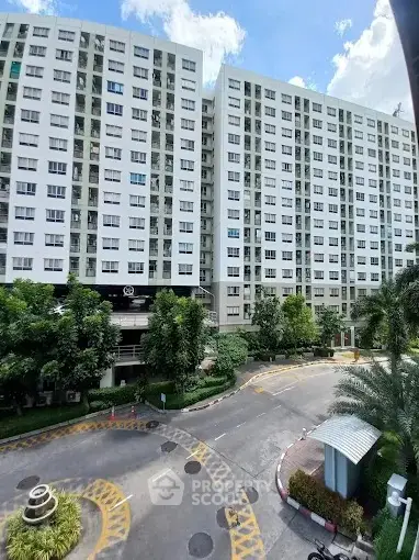 Modern high-rise residential building with lush greenery and clear blue sky.