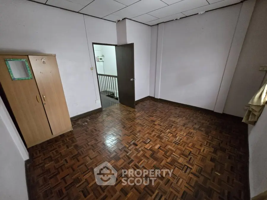 Spacious empty room with parquet flooring and wardrobe, ideal for customization.