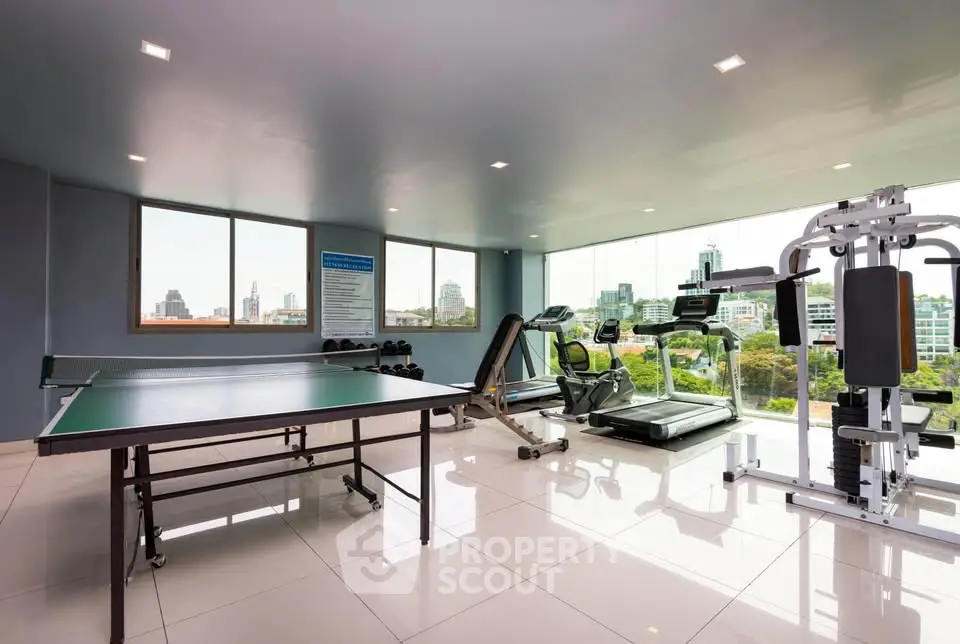 Modern gym with city view featuring treadmills and table tennis setup.