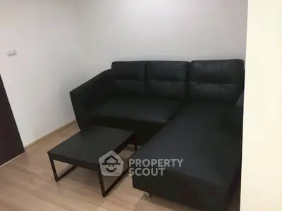 Modern living room with sleek black sectional sofa and minimalist coffee table.