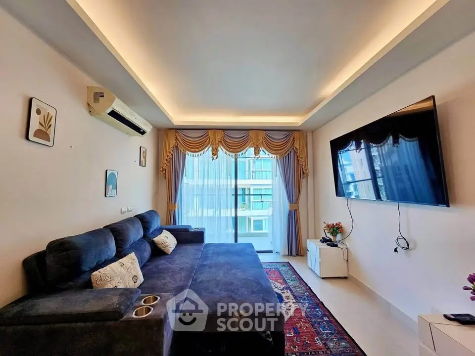 Spacious living room with modern decor, large TV, and elegant curtains in a high-rise apartment.