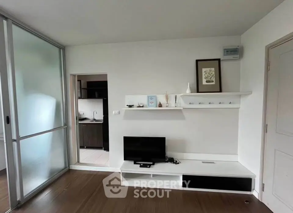 Modern living room with sleek TV stand and sliding glass door leading to kitchen