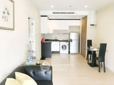 Modern open-plan living room with kitchen, featuring sleek furniture and appliances.