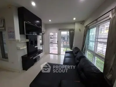 Spacious living room with modern black sofa and large windows offering natural light.