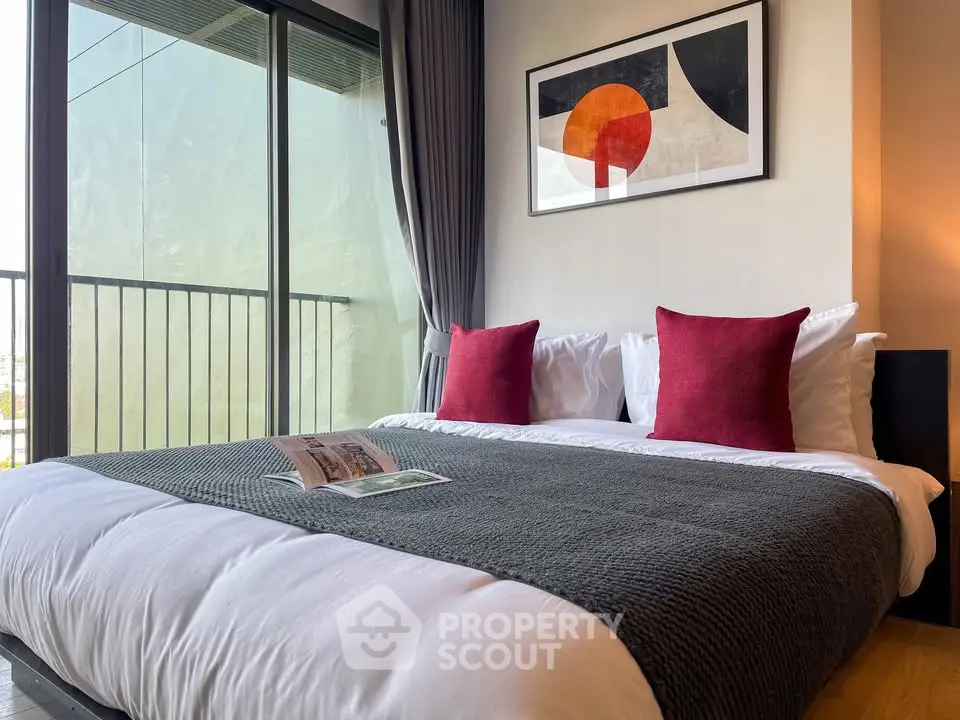 Modern bedroom with stylish decor and balcony view, featuring cozy bedding and contemporary artwork.