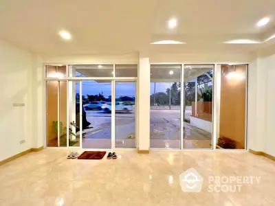 Spacious modern living room with large windows and tiled flooring offering a bright and airy ambiance.