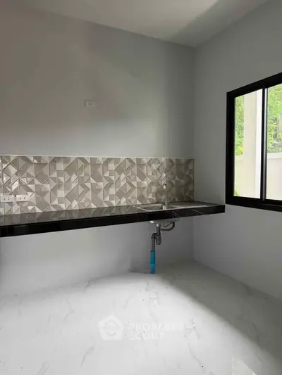 Modern minimalist kitchen with geometric backsplash and sleek black countertop.