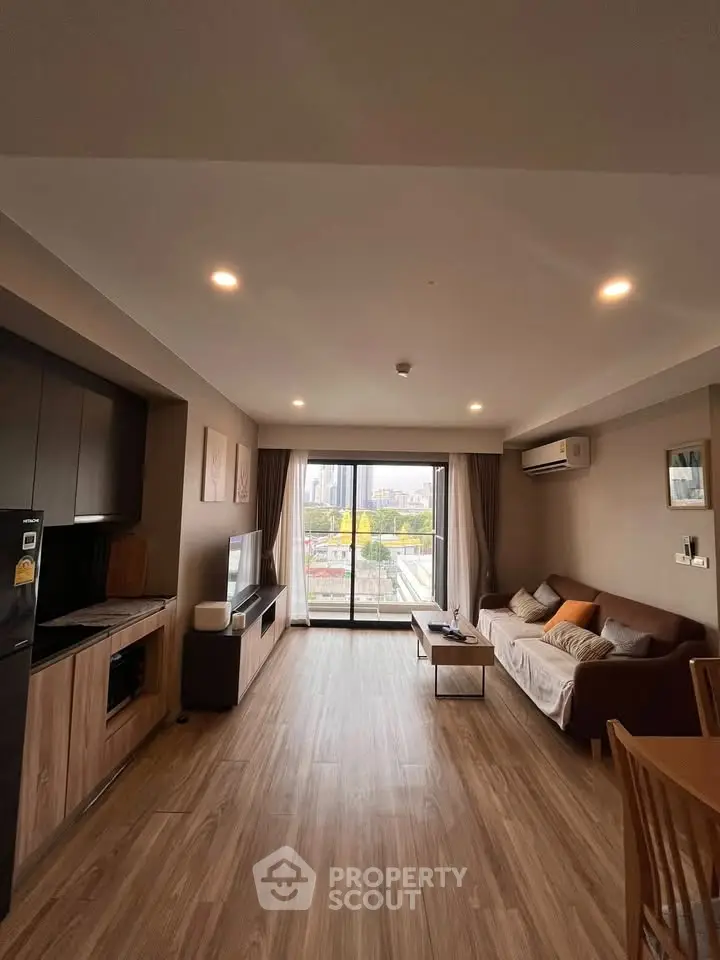 Spacious modern living room with large windows and wooden flooring, offering a cozy and inviting atmosphere.