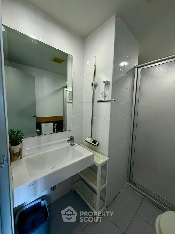 Modern bathroom with sleek white tiles and glass shower enclosure