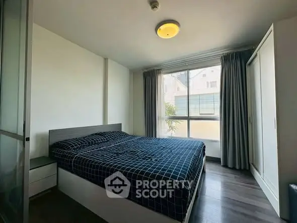 Cozy bedroom with large window and modern furnishings in a bright apartment.